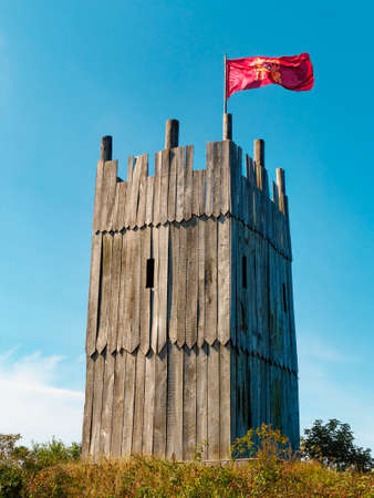 Wooden tower of viking village with viking flag waving against clear blue skyの写真素材