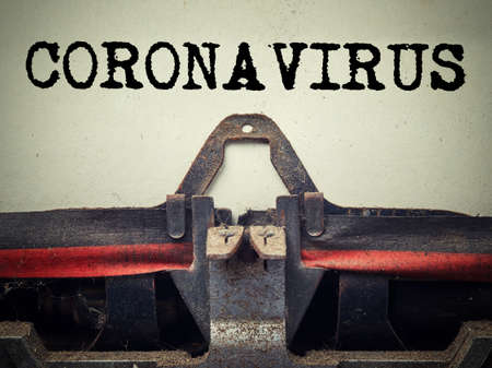 Coronavirus typed on retro typewriter close up. Covid-19 new omicron virus variantの写真素材
