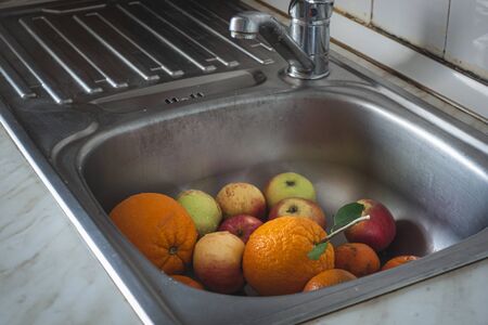 washed and clean fresh orange apple and mandarin in kitchen sink in kitchen sinkの写真素材