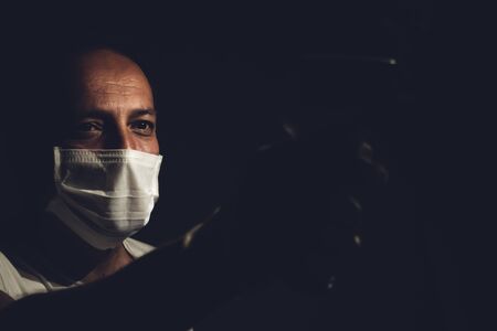 Senior healthcare worker measuring a young adults body temperature with infrared thermometer to test if he has coronavirusの写真素材