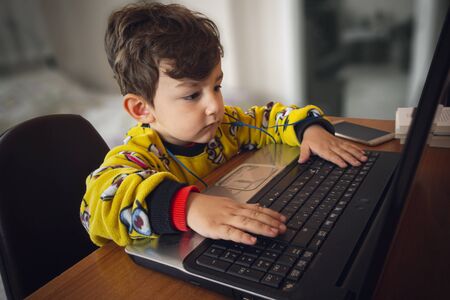 3 years old cute Turkish baby wearing yellow pajamas watching cartoon from laptop