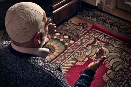 Very old bearded Turkish Muslim man at his 80&#39;s with a prayer cap praying to Allah at his home on his prayer in Ramadan monthの写真素材