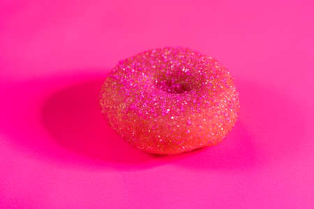 Close up of donut decorated with pink sugar on a pink background.の写真素材