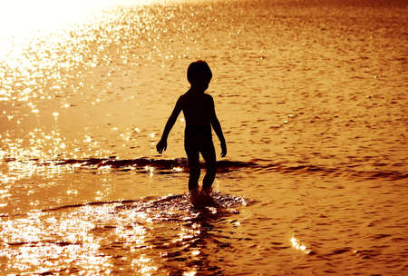 Child in the water at sunsetの写真素材