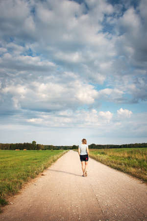 Woman walking on the country roadの写真素材