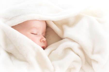 little boy sleeping on soft white blanketの写真素材