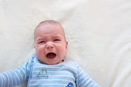 little boy crying on soft white blanket