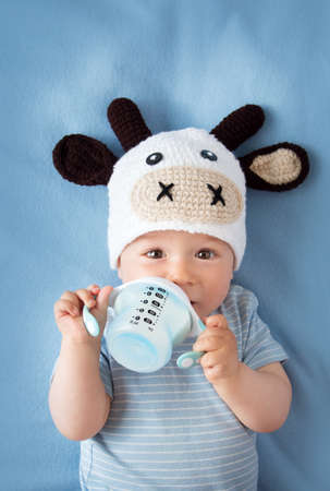 cute baby in a cow hat drinking milkの写真素材
