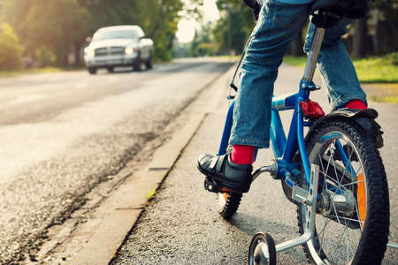A boy on bike and a car on the roadの写真素材