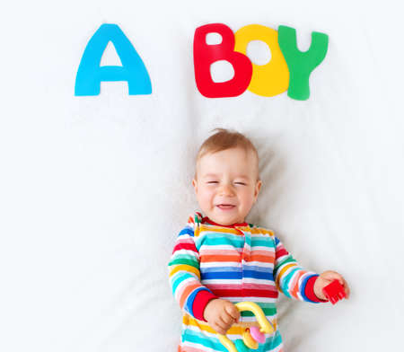 Baby boy lying on soft blanket with letters aboveの写真素材