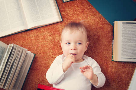One year old baby among books on a blanketの写真素材