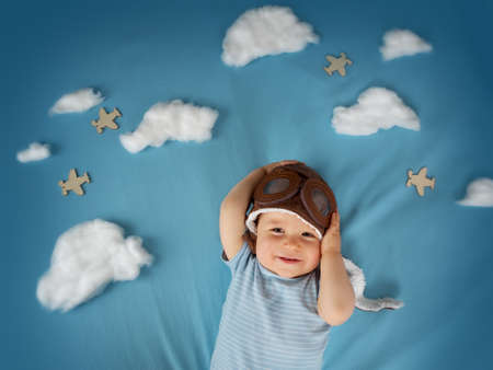 boy lying on blanket with white clouds in pilot hatの写真素材