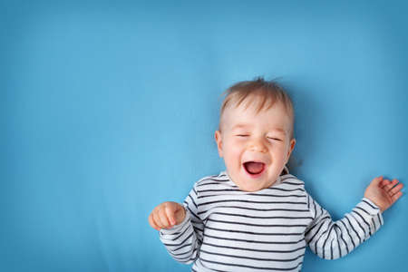 happy little boy on blue blanket background