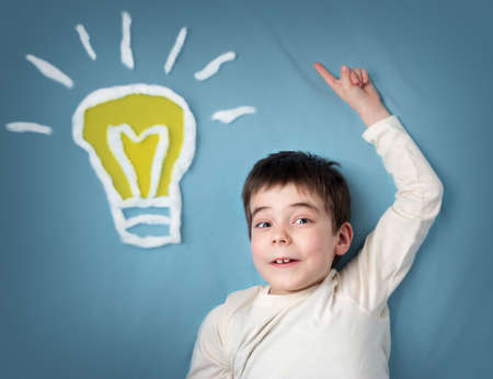 seven years old boy with a bulb on blue background. Child with an ideaの写真素材