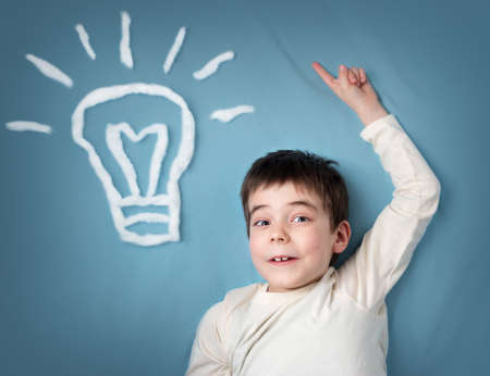 seven years old boy with a bulb on blue background. Child with an ideaの写真素材