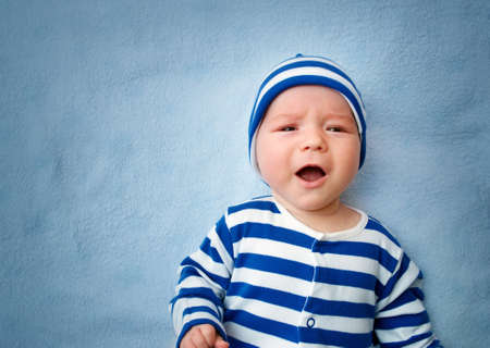 sleepy little boy crying on soft blue blanketの写真素材