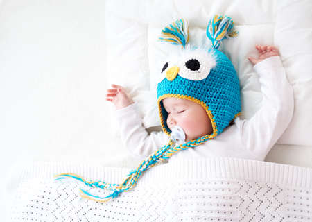 seven month old boy sleeping in the bed in owl hatの写真素材