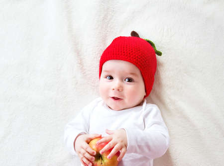 7 month old baby lying inbed with appleの写真素材