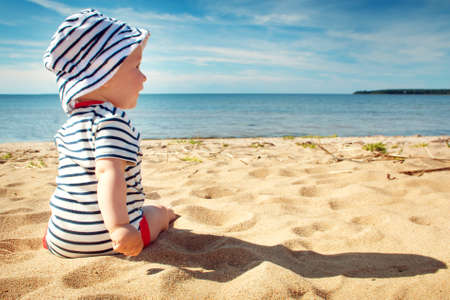 Nine month old baby boy sitting on the beach in beautiful summer dayの写真素材