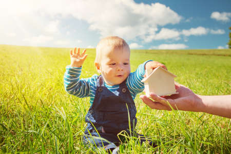little boy with shape of house in beautiful green field on sunny dayの写真素材