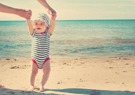 Nine month old baby boy walking on the beach in beautiful summer day
