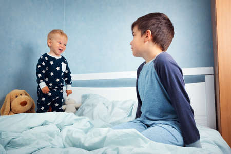 Brothers sitting in the bed in pyjamasの写真素材