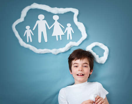 seven years old boy dreaming of a family on blue backgroundの写真素材