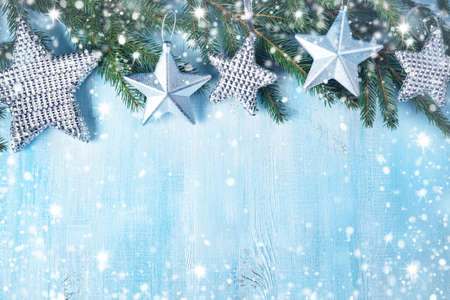 Christmas stars on wooden background with fir tree branches. Winter background