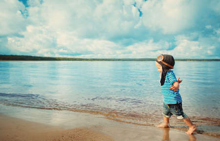 boy playing with a paper plane in aviator hatの写真素材