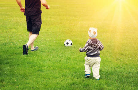Little boy playing football on the field with gatesの写真素材
