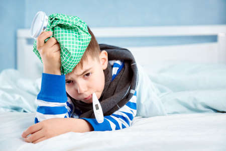 Ill boy lying in bedの写真素材