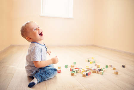 two years old child sitting on the floor with wooden cubesの写真素材
