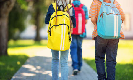 Children with rucksacks standing in the park near schoolの写真素材
