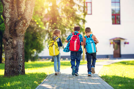 Children with rucksacks standing in the park near schoolの写真素材