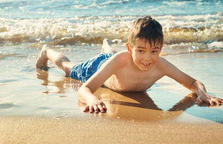 Child lying on the beach with swimming mask and flippers.の写真素材