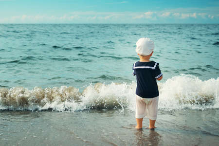 one year old boy walking at the beach in straw hat. Child on family vacations at seaの写真素材