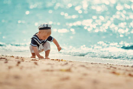 A boy walking at the beach in straw hat.の写真素材