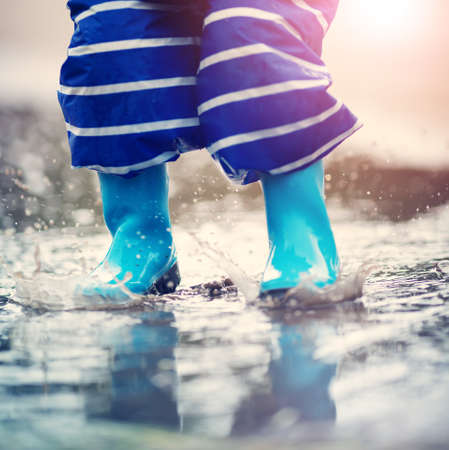 Child walking in wellies in puddle on rainy weatherの写真素材