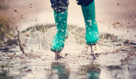 Child walking in wellies in puddle on rainy weatherの写真素材