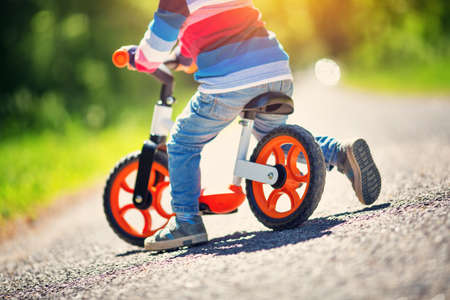 children riding on a bicycles at gravel road in the park in summerの写真素材