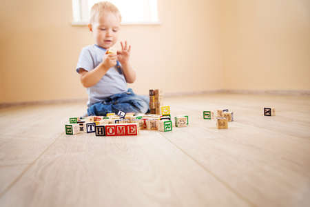 two years old child sitting on the floor with wooden cubesの写真素材