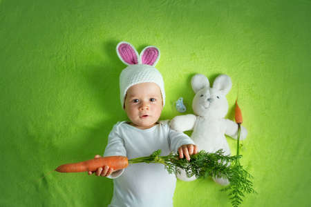 Baby in rabbit hat eating carrot