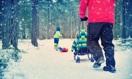 Father with sons walking at snowfallの写真素材