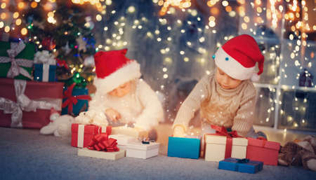 Boy and girl lying on the floor with presents near christmas treeの写真素材