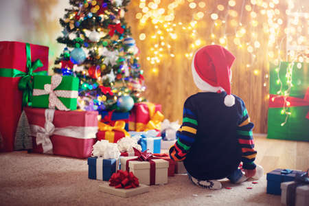 Boy and sitting on the floor with presents near christmas treeの写真素材