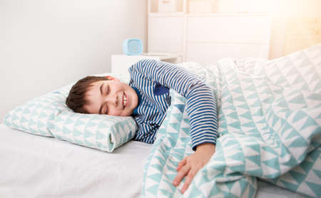eight years old child sleeping in bed on pillow. Boy asleep in white bedroomの写真素材