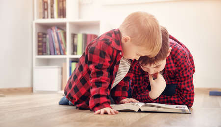 Three years old child sitting among books at homeの写真素材
