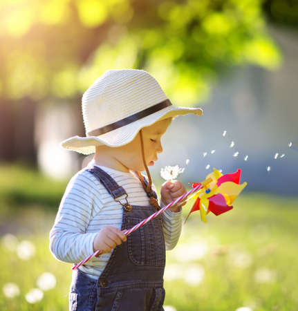 Baby boy standing in grass on the fieald with dandelionsの写真素材