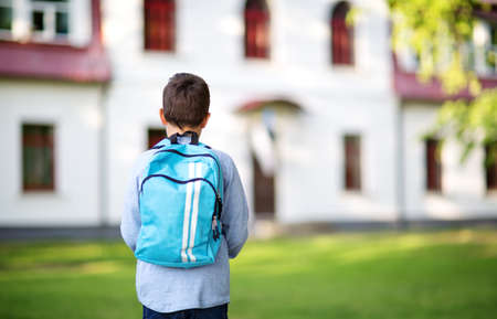 Boy with rucksack infront of a school buildingの写真素材