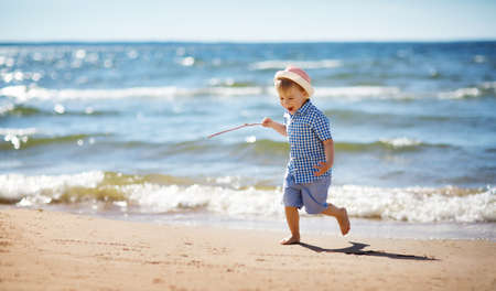 Boy walking at sea in straw hatの写真素材